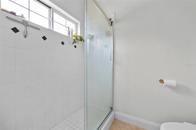 bathroom with a stall shower, toilet, baseboards, and tile patterned flooring