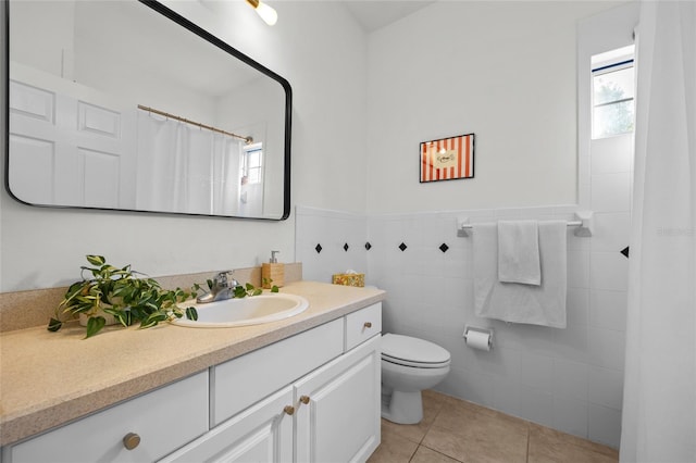 full bath featuring tile patterned flooring, toilet, vanity, tile walls, and a wainscoted wall
