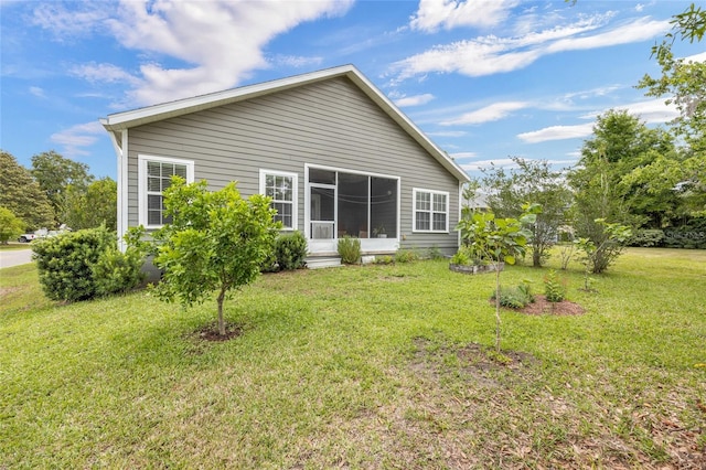rear view of house with a lawn and a sunroom