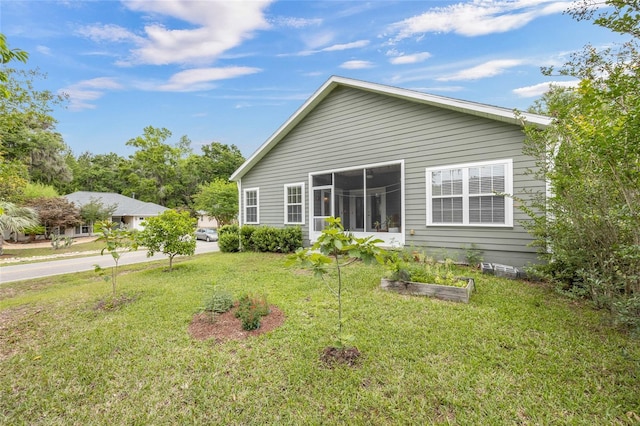 rear view of house with a lawn and a sunroom