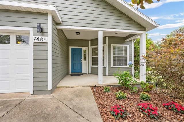 view of exterior entry featuring covered porch and an attached garage