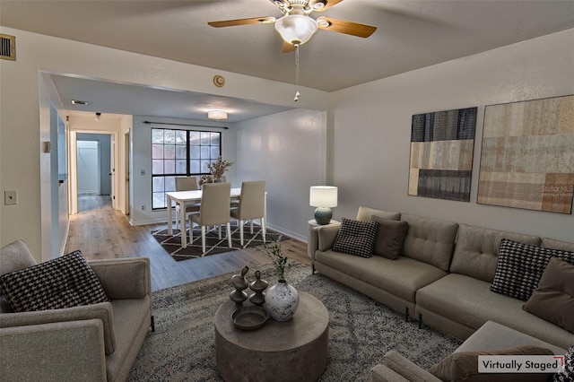 living room with wood finished floors, a ceiling fan, and baseboards