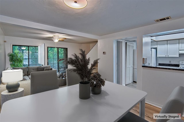 dining room featuring light wood-style flooring, ceiling fan, and baseboards