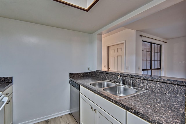 kitchen with stainless steel dishwasher, a sink, and dark countertops