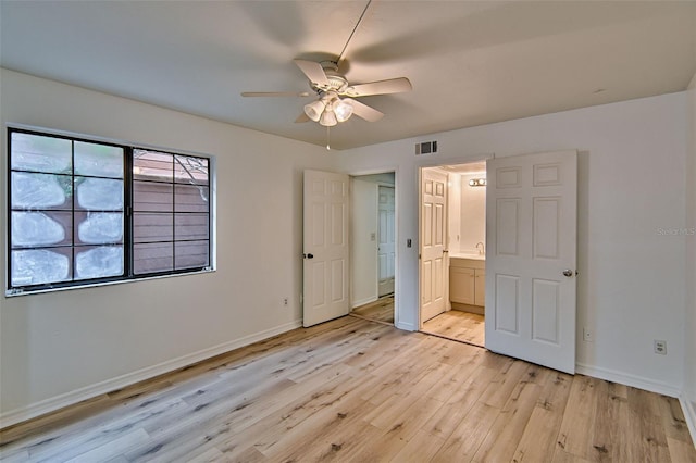 unfurnished bedroom featuring light wood-style flooring, baseboards, ensuite bathroom, and ceiling fan