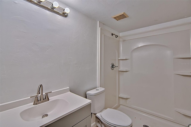 bathroom featuring a shower, toilet, and vanity