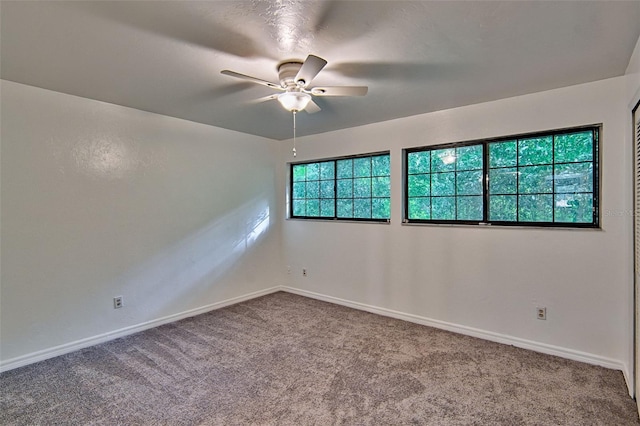 carpeted empty room with ceiling fan and baseboards