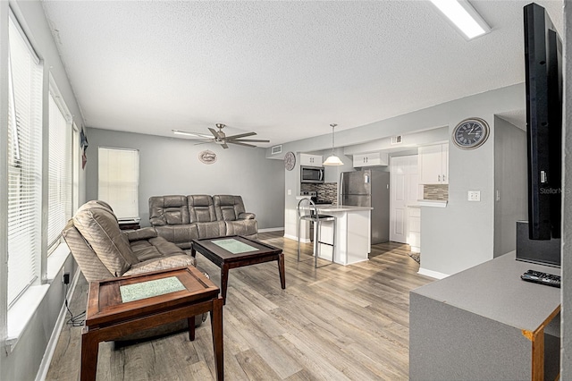2601 SW Archer Rd Unit G 128, Gainesville, FL 32608 - living area featuring light wood-style flooring, ceiling fan, baseboards, and a textured ceiling