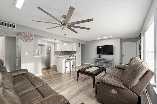 2601 SW Archer Rd Unit G 128, Gainesville, FL 32608 - living room with ceiling fan, baseboards, light wood finished floors, and a textured ceiling