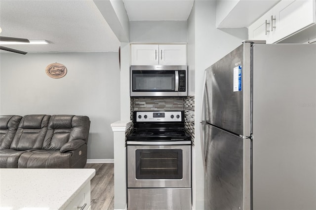 2601 SW Archer Rd Unit G 128, Gainesville, FL 32608 - kitchen featuring appliances with stainless steel finishes, white cabinetry, light wood-type flooring, decorative backsplash, and ceiling fan