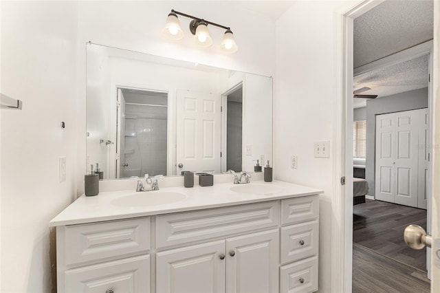 2601 SW Archer Rd Unit G 128, Gainesville, FL 32608 - ensuite bathroom featuring double vanity, a tile shower, a textured ceiling, and wood finished floors