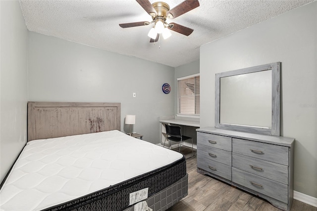 2601 SW Archer Rd Unit G 128, Gainesville, FL 32608 - bedroom featuring wood finished floors, a textured ceiling, baseboards, and ceiling fan