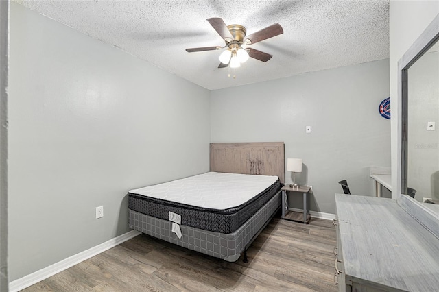 2601 SW Archer Rd Unit G 128, Gainesville, FL 32608 - bedroom with wood finished floors, baseboards, a textured ceiling, and ceiling fan