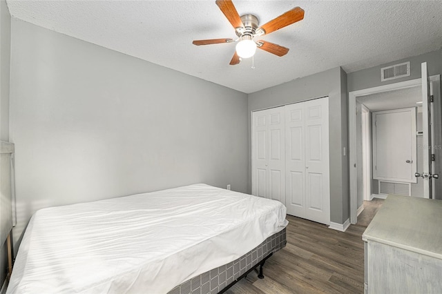 2601 SW Archer Rd Unit G 128, Gainesville, FL 32608 - bedroom featuring dark wood-type flooring, a textured ceiling, a closet, ceiling fan, and baseboards
