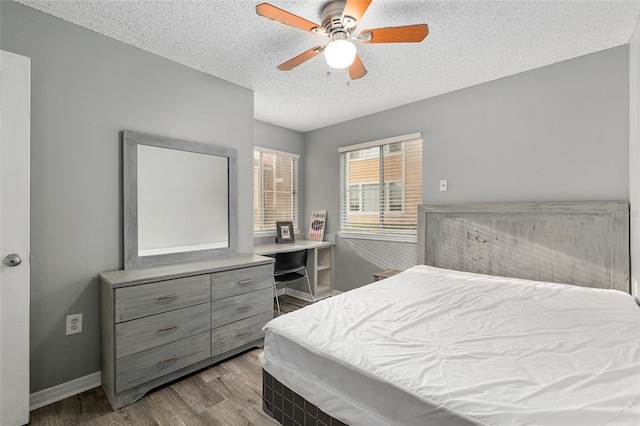 2601 SW Archer Rd Unit G 128, Gainesville, FL 32608 - bedroom with wood finished floors, a textured ceiling, a ceiling fan, and baseboards