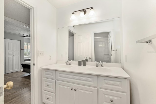 2601 SW Archer Rd Unit G 128, Gainesville, FL 32608 - bathroom with double vanity, wood finished floors, a textured ceiling, ceiling fan, and a shower