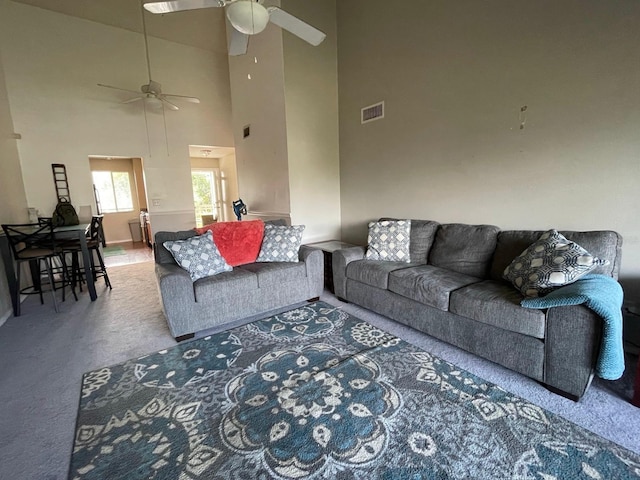 living room featuring a ceiling fan, carpet floors, a towering ceiling, and baseboards