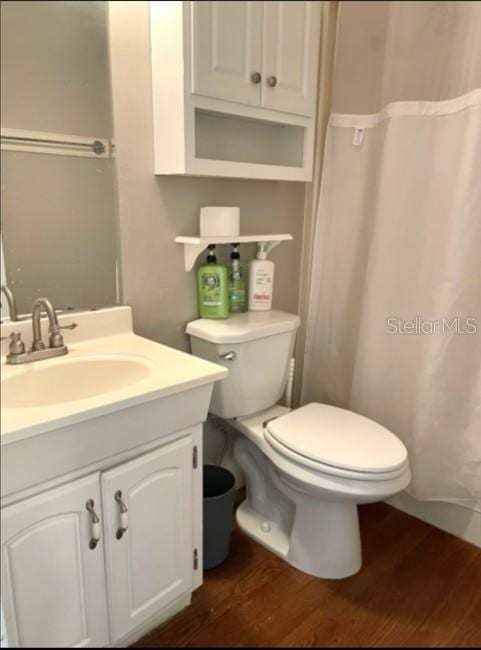 bathroom with wood finished floors, toilet, vanity, and a shower with curtain