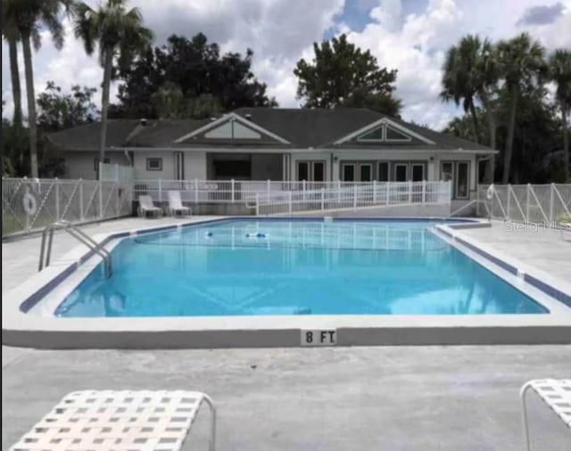 community pool with fence, a patio area, and french doors