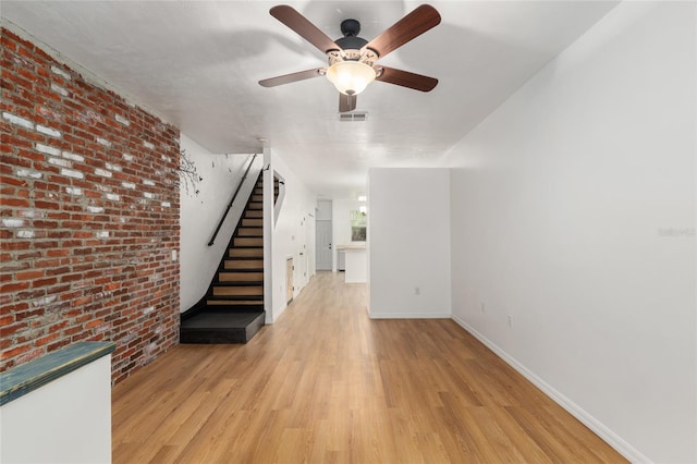 4415 SW 34th St Unit 503, Gainesville, FL 32608 - unfurnished living room with stairs, light wood-type flooring, a ceiling fan, baseboards, and brick wall