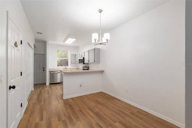 4415 SW 34th St Unit 503, Gainesville, FL 32608 - kitchen featuring stainless steel appliances, a chandelier, light wood finished floors, light countertops, and a peninsula