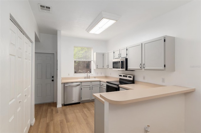 4415 SW 34th St Unit 503, Gainesville, FL 32608 - kitchen with appliances with stainless steel finishes, a sink, light wood-style flooring, a peninsula, and light countertops