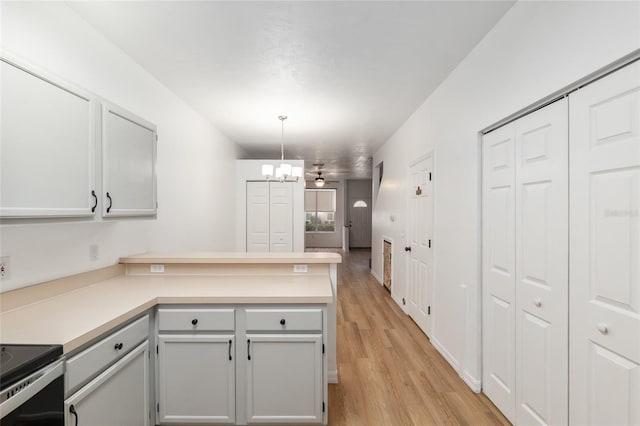 4415 SW 34th St Unit 503, Gainesville, FL 32608 - kitchen with a peninsula, light countertops, light wood-type flooring, a chandelier, and hanging light fixtures