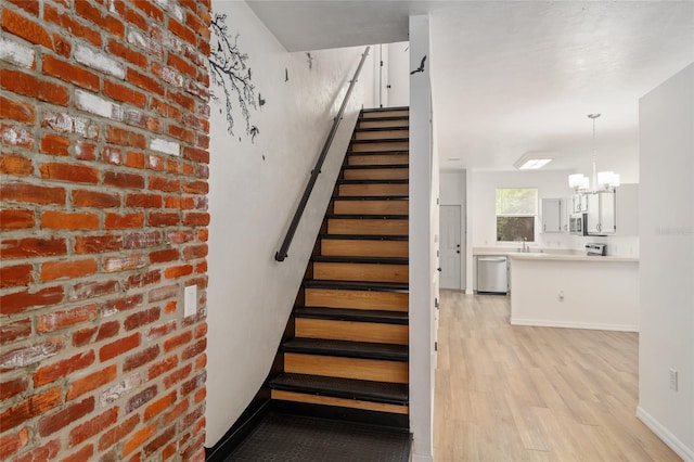 4415 SW 34th St Unit 503, Gainesville, FL 32608 - staircase featuring wood finished floors, a chandelier, and baseboards