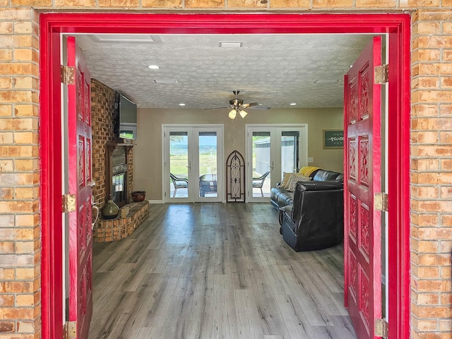 7972 State Rd Unit 100, Keystone Heights, FL 32656 - living room with french doors, a brick fireplace, wood finished floors, a ceiling fan, and brick wall