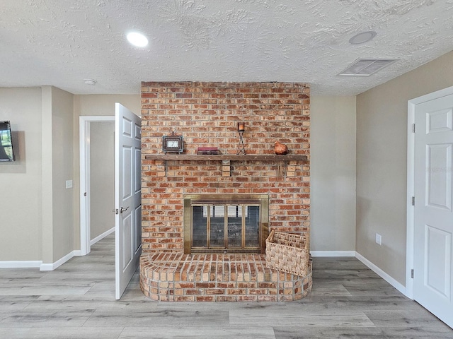 7972 State Rd Unit 100, Keystone Heights, FL 32656 - unfurnished living room with wood finished floors, baseboards, a textured ceiling, and a brick fireplace