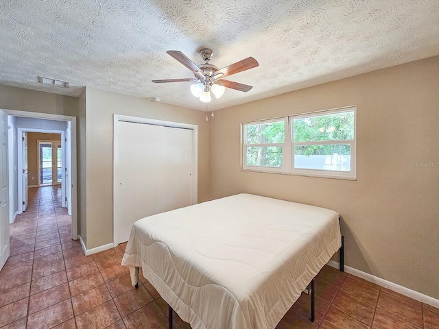 7972 State Rd Unit 100, Keystone Heights, FL 32656 - bedroom with baseboards, tile patterned flooring, a closet, a ceiling fan, and a textured ceiling