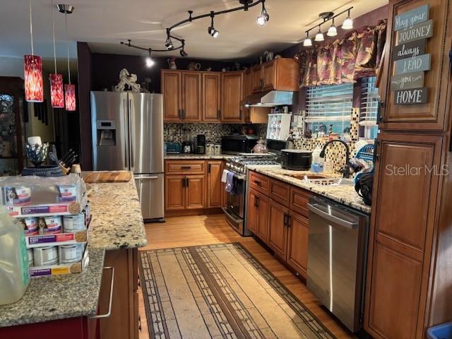 6410 SW 170th St, Archer, FL 32618 - kitchen featuring stainless steel appliances, a sink, extractor fan, brown cabinetry, and light wood-style flooring