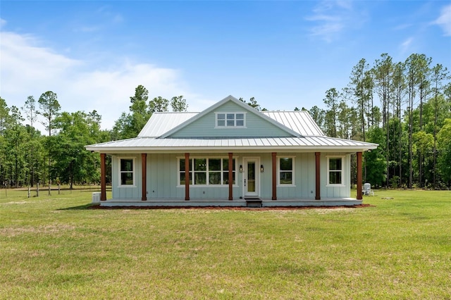 view of front of home with board and batten siding, a porch, a front yard, and metal roof
