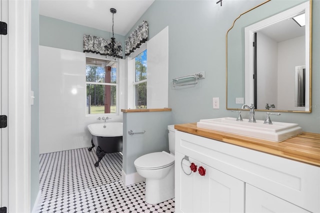 bathroom featuring a freestanding tub, toilet, a chandelier, and vanity