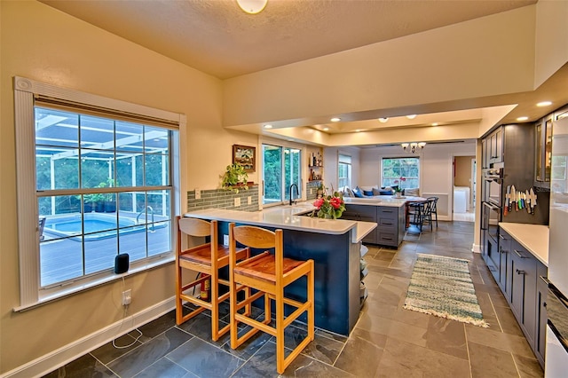 20250 NW 71st Ct, Micanopy, FL 32667 - kitchen featuring a peninsula, baseboards, light countertops, a breakfast bar area, and a sink