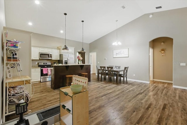 1180 Hough St, Bell, FL 32619 - kitchen with appliances with stainless steel finishes, wood finished floors, arched walkways, light countertops, and high vaulted ceiling