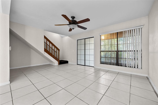 5841 SW 8th Pl, Gainesville, FL 32607 - unfurnished living room featuring ceiling fan, stairs, baseboards, and tile patterned floors
