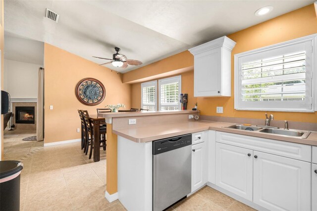 1979 NW 86th Ter, Gainesville, FL 32606 - kitchen with stainless steel dishwasher, a peninsula, a sink, ceiling fan, and a lit fireplace