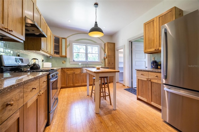 502 NE Cholokka Blvd, Micanopy, FL 32667 - kitchen with appliances with stainless steel finishes, wall chimney range hood, light wood finished floors, backsplash, and a sink