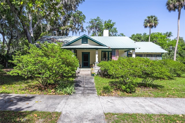 502 NE Cholokka Blvd, Micanopy, FL 32667 - view of front facade with covered porch, a chimney, and a metal roof