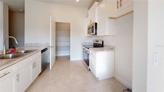 3279 E Iris Ln, Bell, FL 32619 - kitchen with stainless steel appliances, a sink, light tile patterned floors, white cabinets, and baseboards
