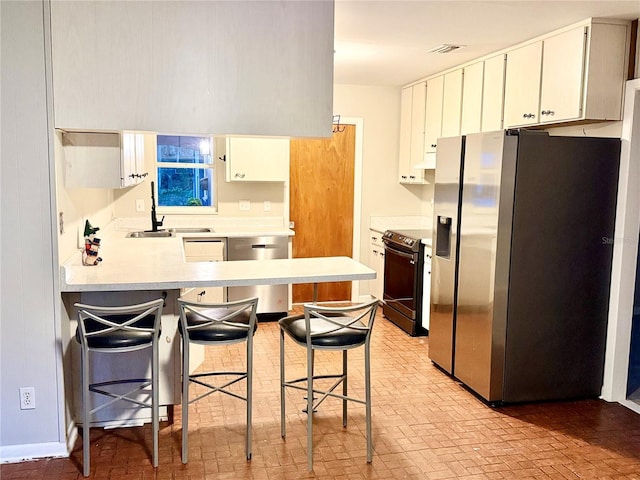 532 NE 7th Ter, Gainesville, FL 32601 - kitchen with stainless steel appliances, brick patterned floors, a peninsula, light countertops, and a kitchen breakfast bar