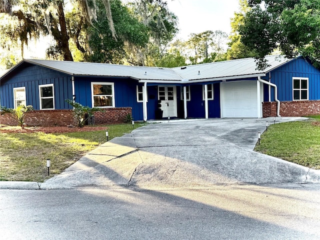 532 NE 7th Ter, Gainesville, FL 32601 - ranch-style house featuring an attached garage, board and batten siding, concrete driveway, a front lawn, and brick siding