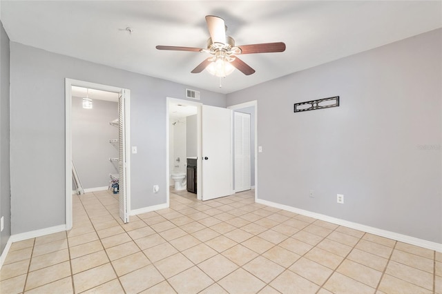2360 SW Archer Rd Unit 1102, Gainesville, FL 32608 - unfurnished bedroom with a walk in closet, a closet, baseboards, a ceiling fan, and connected bathroom