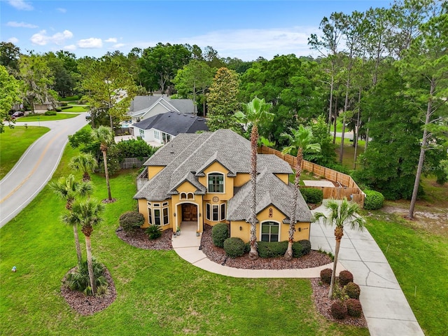view of front facade with stucco siding, concrete driveway, a shingled roof, and a front lawn