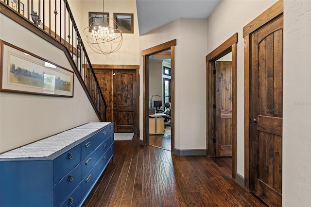 foyer with a chandelier, dark wood finished floors, baseboards, and stairs