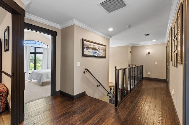 hall with an upstairs landing, wood-type flooring, baseboards, crown molding, and recessed lighting