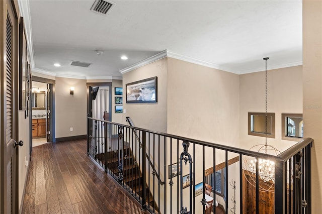 hallway with an upstairs landing, dark wood-style floors, baseboards, ornamental molding, and recessed lighting