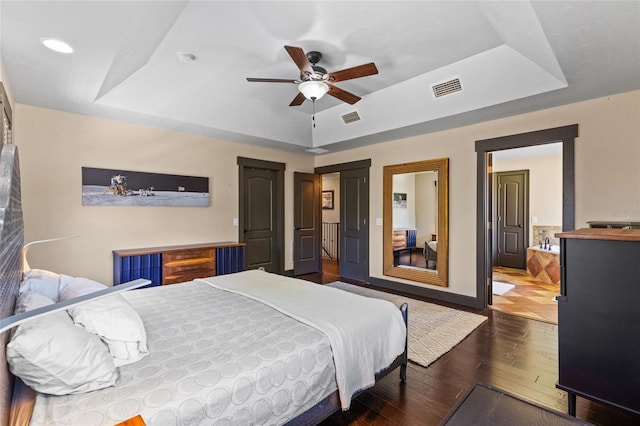 bedroom featuring a raised ceiling, wood-type flooring, baseboards, ceiling fan, and recessed lighting