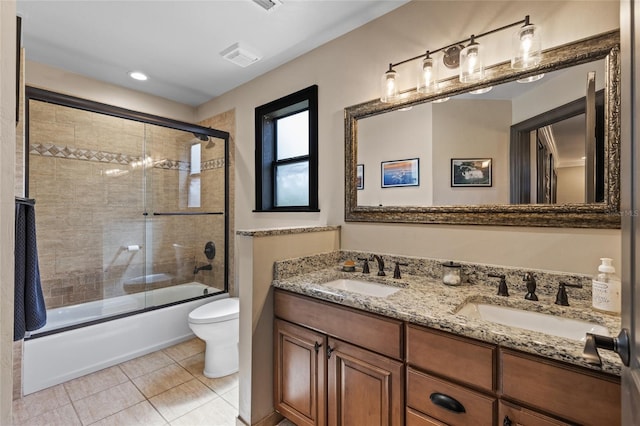 full bath featuring tile patterned floors, shower / bath combination with glass door, double vanity, and toilet